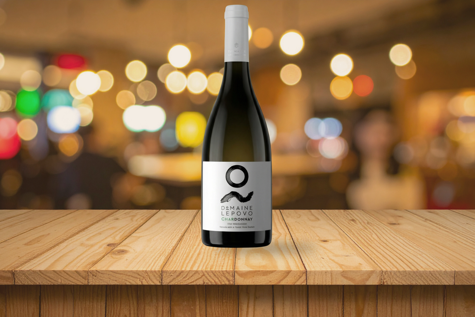 Bottle of Lepovo Chardonnay Terroir 2021 on a dining table with a glass of white wine and warm ambient lighting