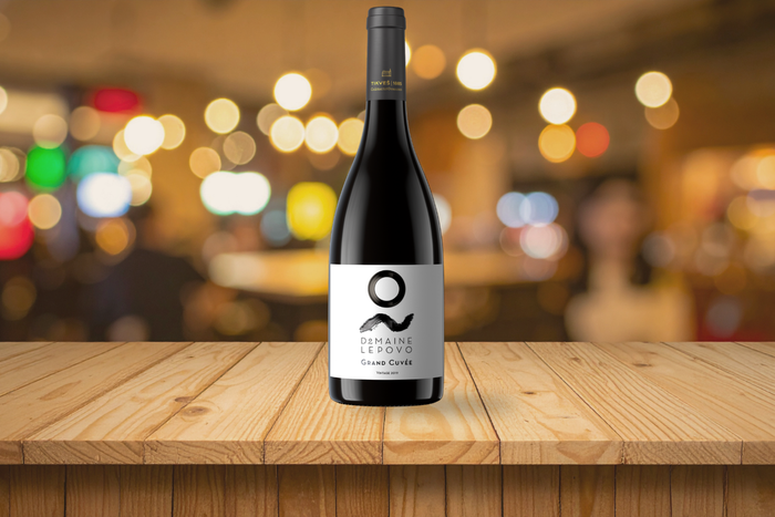 Bottle of Lepovo Grand Cuvée Terroir 2021 on a wooden table with warm ambient lighting