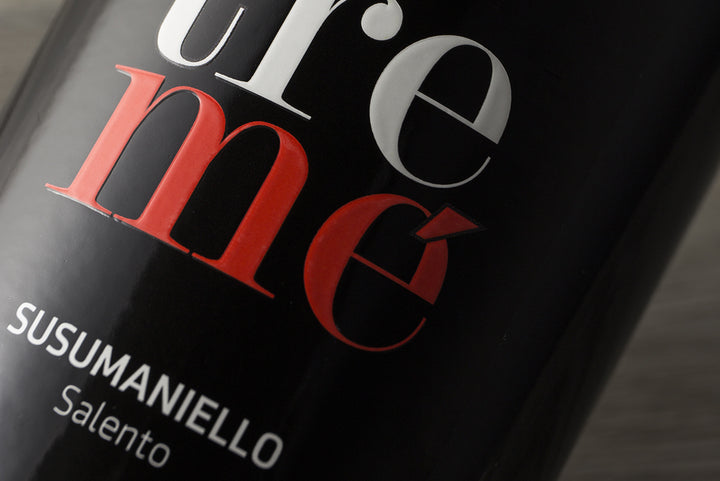 Close-up of a black bottle label with stylized red and white text reading 'SUSUMANIELLO' and 'Salento'.